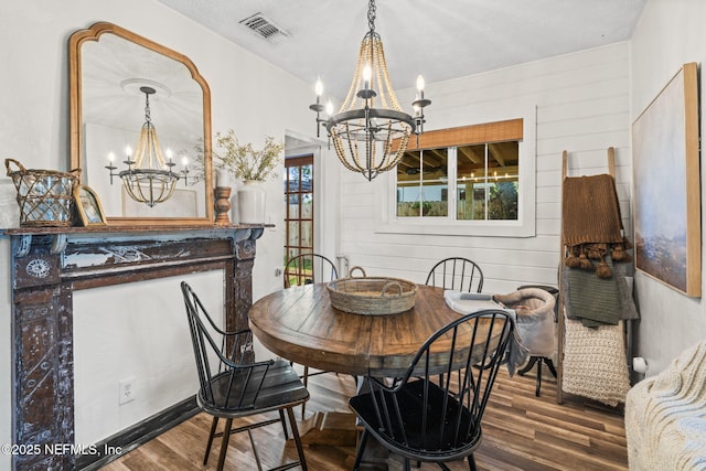 dining space featuring an inviting chandelier, wood finished floors, and visible vents