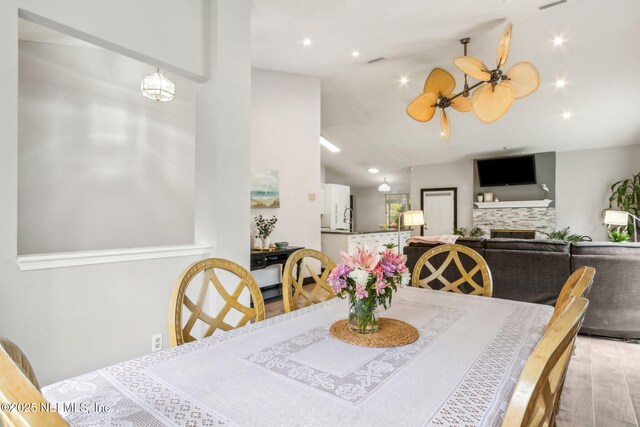 dining room with recessed lighting, a tile fireplace, ceiling fan, light wood-style flooring, and lofted ceiling