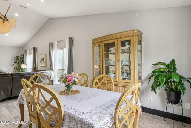 dining room featuring visible vents, light wood-style flooring, and lofted ceiling