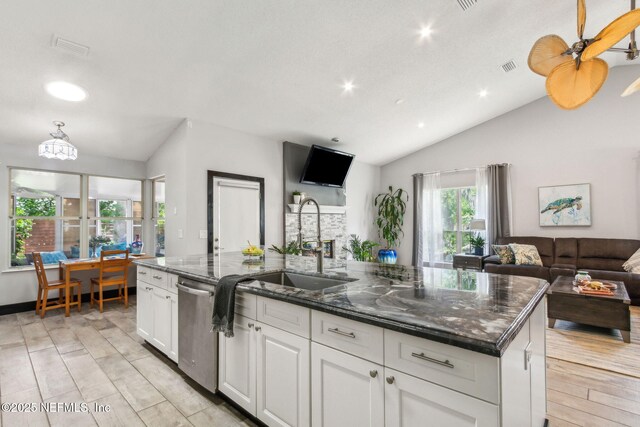 kitchen with a sink, open floor plan, white cabinetry, stainless steel dishwasher, and lofted ceiling