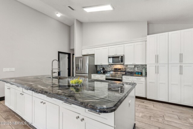kitchen featuring a sink, light wood-style flooring, stainless steel appliances, and tasteful backsplash