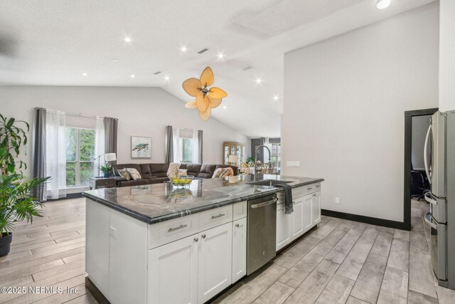 kitchen featuring white cabinetry, a sink, light wood-style floors, stainless steel appliances, and open floor plan