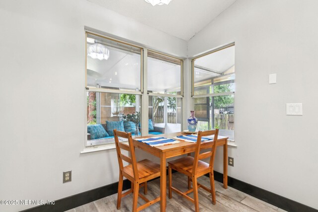 dining space featuring baseboards, vaulted ceiling, wood finished floors, and a healthy amount of sunlight