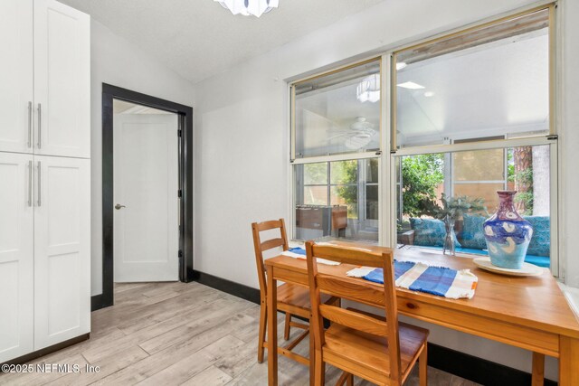 dining space featuring light wood-style flooring, a ceiling fan, vaulted ceiling, and baseboards