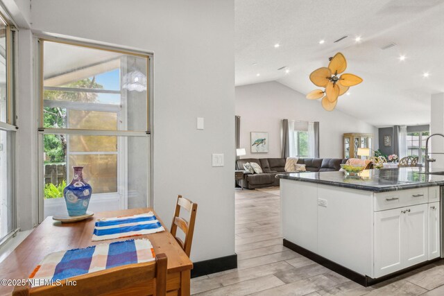 kitchen with light wood-style flooring, vaulted ceiling, a wealth of natural light, and white cabinetry