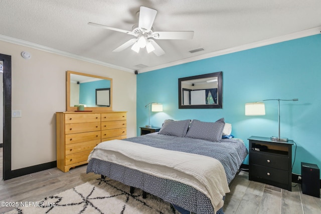 bedroom with visible vents, wood finished floors, ornamental molding, and baseboards