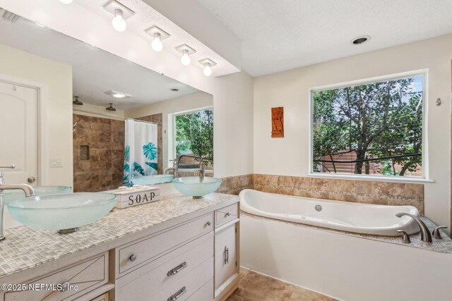 bathroom featuring a tile shower, a garden tub, double vanity, and a sink