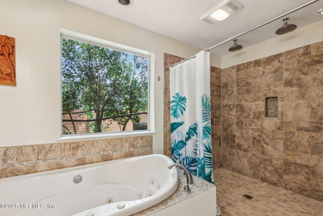bathroom with a textured ceiling, visible vents, a jetted tub, and tiled shower