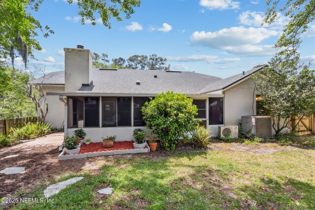 rear view of property with a chimney, a lawn, central air condition unit, fence, and a sunroom