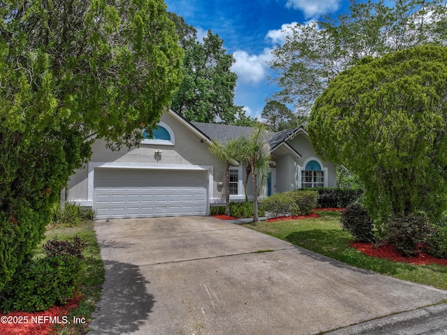 ranch-style home featuring an attached garage, driveway, and stucco siding