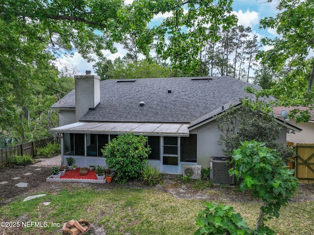 rear view of property featuring a sunroom, a shingled roof, central AC, and a fenced backyard