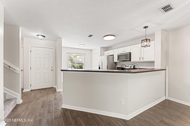 1605 Vineland Cir Unit B, Fleming Island, FL 32003 - kitchen featuring white cabinets, dark countertops, wood finished floors, visible vents, and appliances with stainless steel finishes