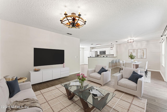 1605 Vineland Cir Unit B, Fleming Island, FL 32003 - living room with an inviting chandelier, visible vents, light wood-type flooring, baseboards, and a textured ceiling