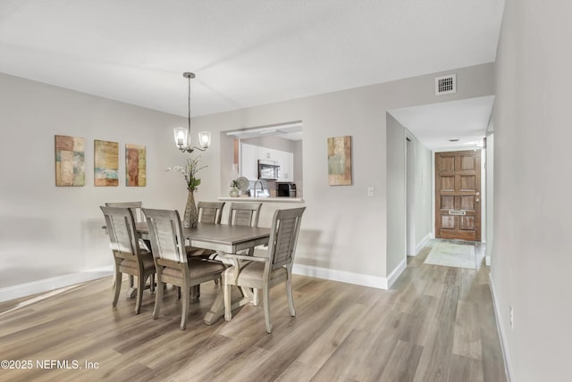 7908 Los Robles Ct Unit 7908, Jacksonville, FL 32256 - dining room featuring a chandelier, visible vents, light wood finished floors, and baseboards