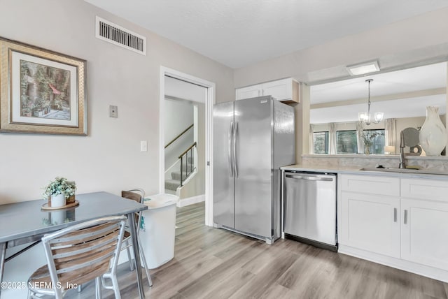 7908 Los Robles Ct Unit 7908, Jacksonville, FL 32256 - kitchen featuring stainless steel appliances, visible vents, light wood-style flooring, white cabinetry, and light countertops