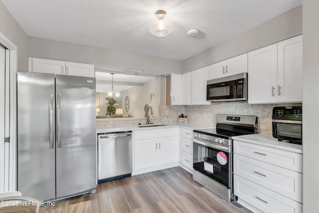 7908 Los Robles Ct Unit 7908, Jacksonville, FL 32256 - kitchen featuring white cabinets, a sink, appliances with stainless steel finishes, light wood-style floors, and light countertops