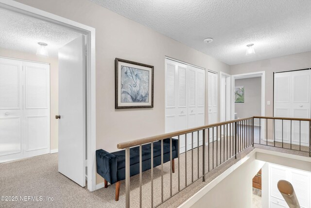 7908 Los Robles Ct Unit 7908, Jacksonville, FL 32256 - hall with an upstairs landing, a textured ceiling, carpet flooring, and baseboards