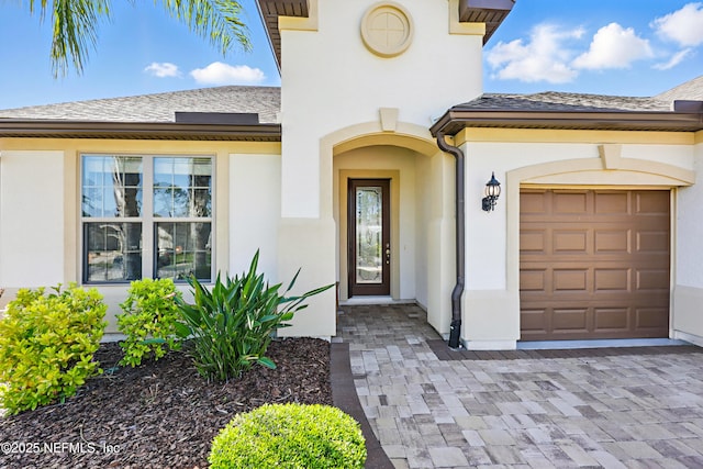 view of exterior entry featuring a garage and stucco siding