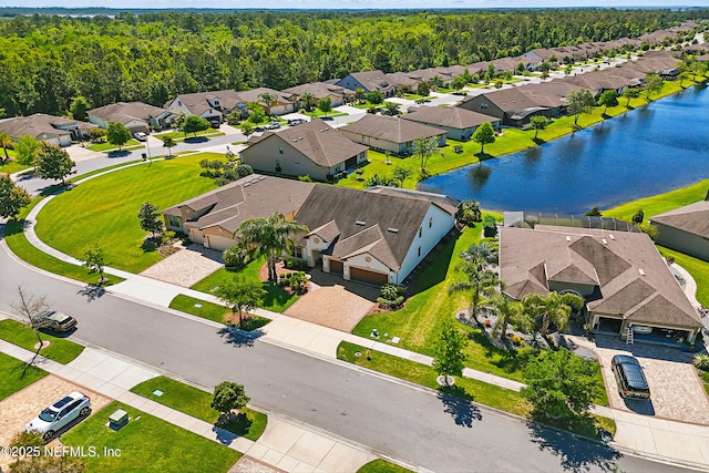 aerial view featuring a water view, a view of trees, and a residential view