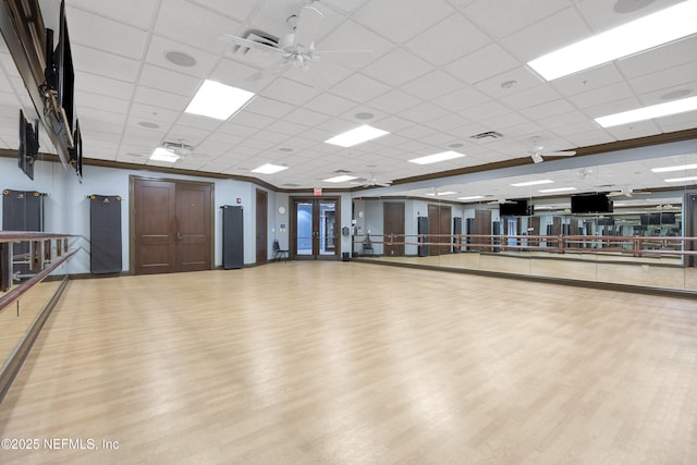 exercise room featuring a ceiling fan, a drop ceiling, wood finished floors, and visible vents