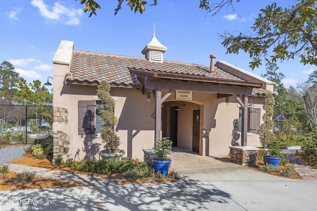 mediterranean / spanish-style house featuring stucco siding, fence, and a tile roof
