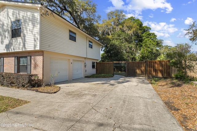2848 Cedarcrest Dr, Orange Park, FL 32073 - view of side of home featuring a gate, fence, driveway, brick siding, and a garage
