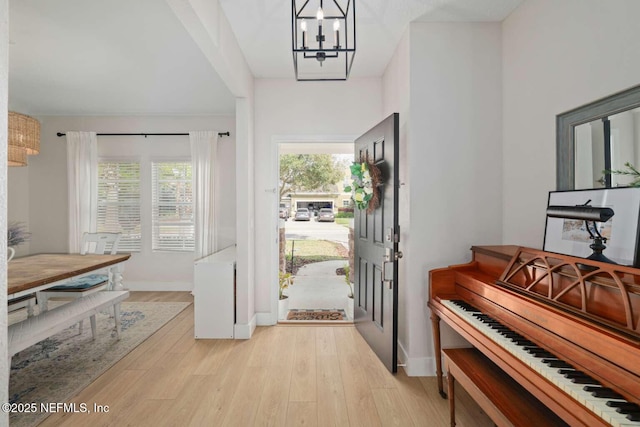 entryway featuring baseboards, a notable chandelier, and light wood finished floors