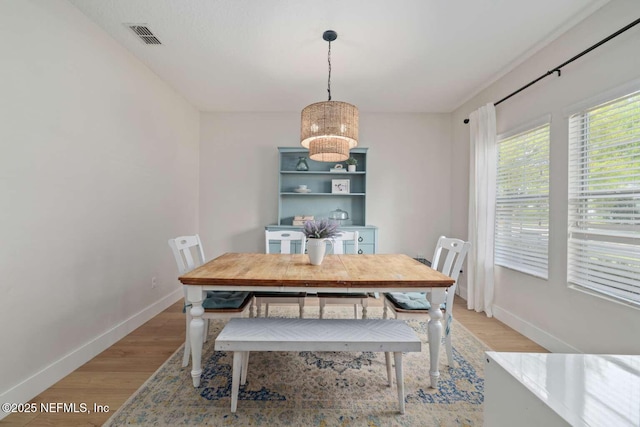 dining space with light wood-style flooring, visible vents, baseboards, and a notable chandelier