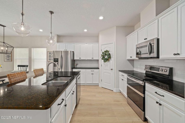 kitchen featuring a sink, stainless steel appliances, light wood-style flooring, backsplash, and recessed lighting