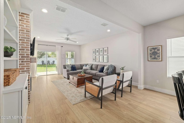 living room featuring light wood finished floors, baseboards, visible vents, and ceiling fan