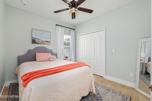 bedroom featuring ceiling fan, baseboards, light wood-style floors, and a closet