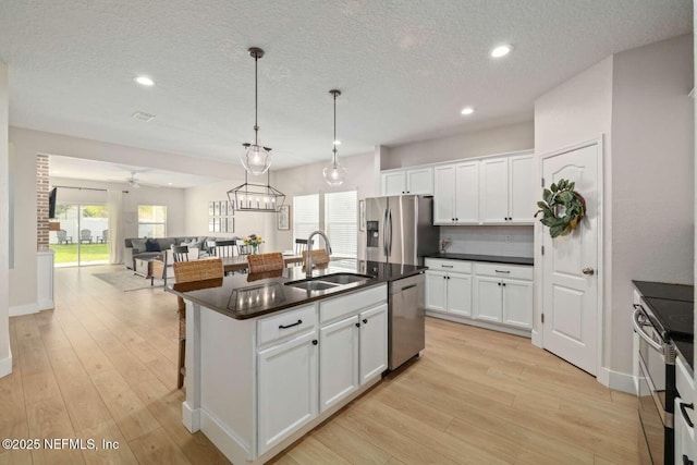 120 Corey Cay Ave, Saint Augustine, FL 32092 - kitchen with stainless steel appliances, a sink, dark countertops, light wood-style floors, and white cabinetry