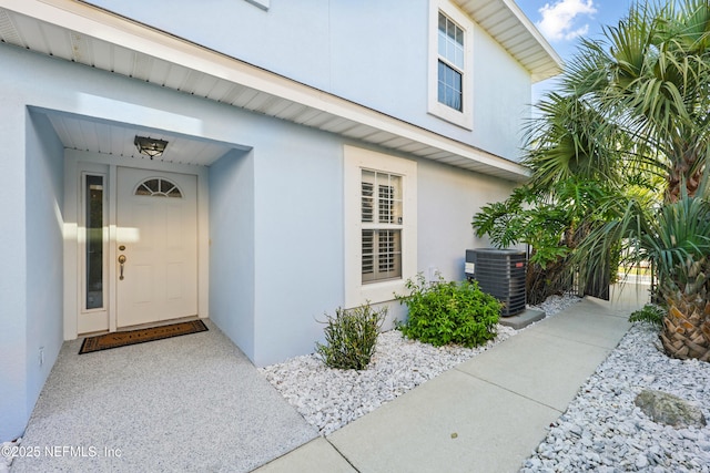 doorway to property with cooling unit and stucco siding