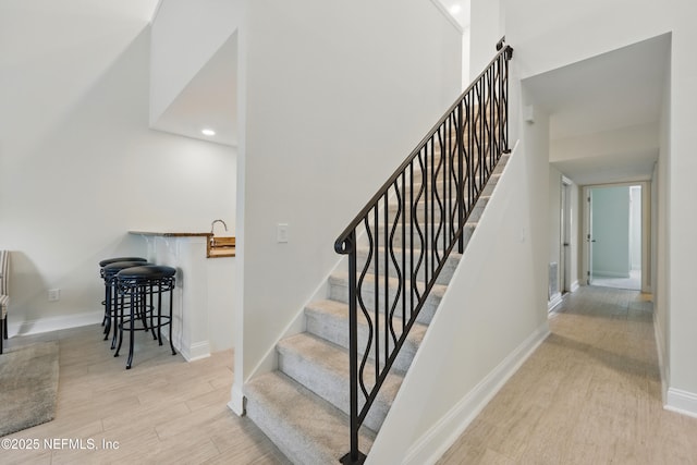 stairs featuring baseboards, wood finished floors, and recessed lighting