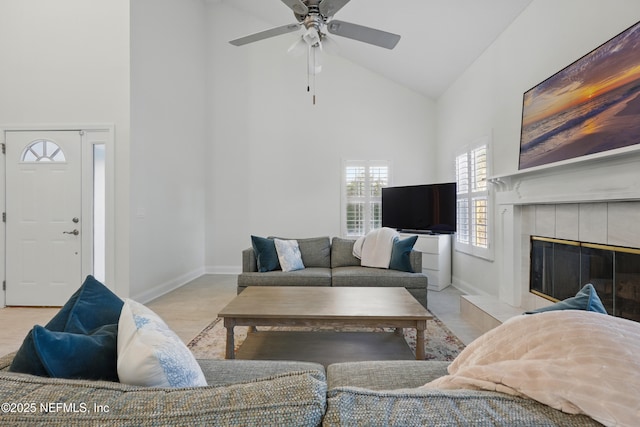 living area featuring a fireplace, baseboards, high vaulted ceiling, and ceiling fan