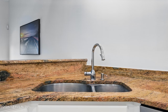 interior details with white cabinets, stainless steel dishwasher, and a sink