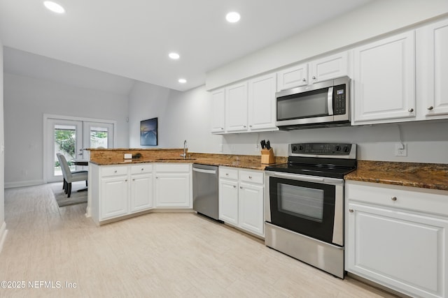 kitchen featuring a peninsula, white cabinetry, stainless steel appliances, and recessed lighting