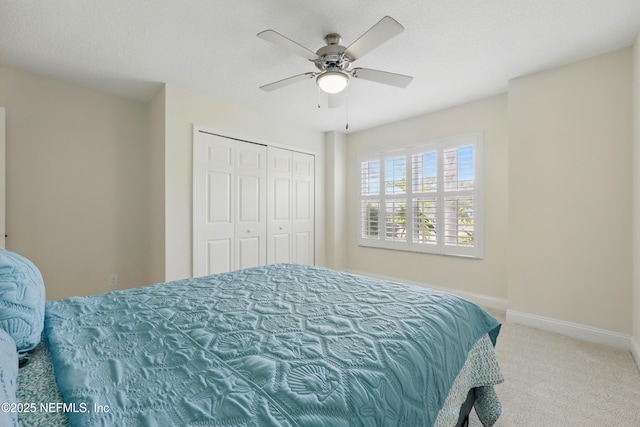 carpeted bedroom with ceiling fan, baseboards, and a closet