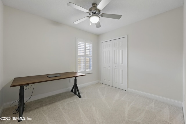 unfurnished office featuring ceiling fan, baseboards, and light colored carpet