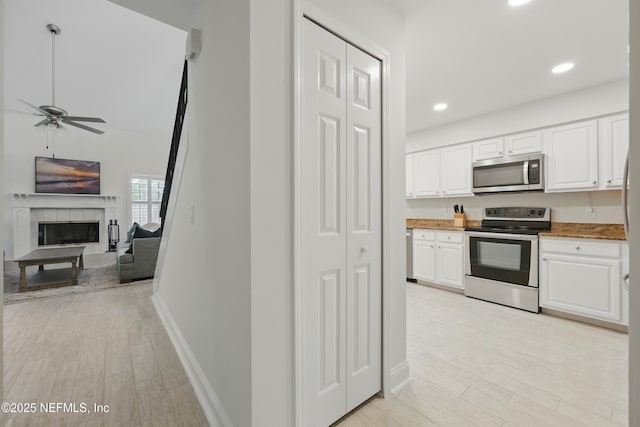 kitchen with white cabinets, light wood-style flooring, appliances with stainless steel finishes, and a ceiling fan