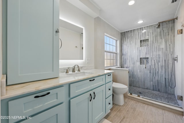 full bathroom featuring vanity, a tile shower, toilet, visible vents, and recessed lighting