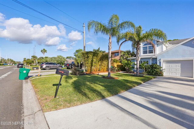 view of front of property featuring an attached garage, driveway, a front yard, and stucco siding