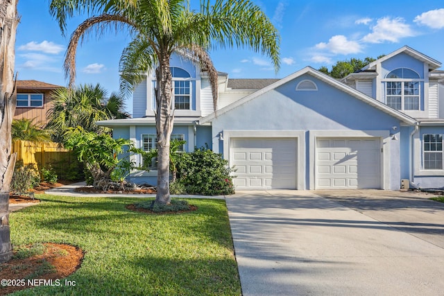 traditional-style house with stucco siding, an attached garage, driveway, and a front yard