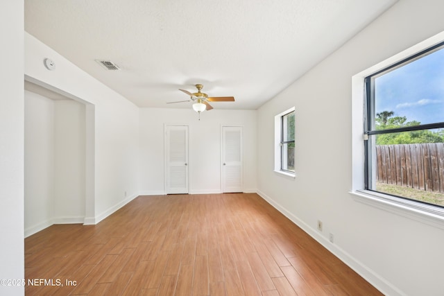 12054 Correa Ct, Jacksonville, FL 32246 - empty room featuring light wood-style flooring, visible vents, a ceiling fan, and a healthy amount of sunlight