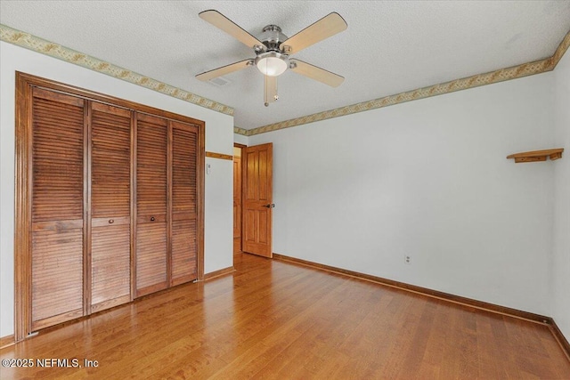 unfurnished bedroom with baseboards, a ceiling fan, light wood-type flooring, and a closet