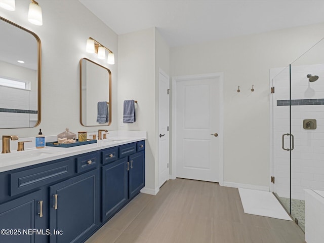 full bath featuring baseboards, a sink, double vanity, and a stall shower