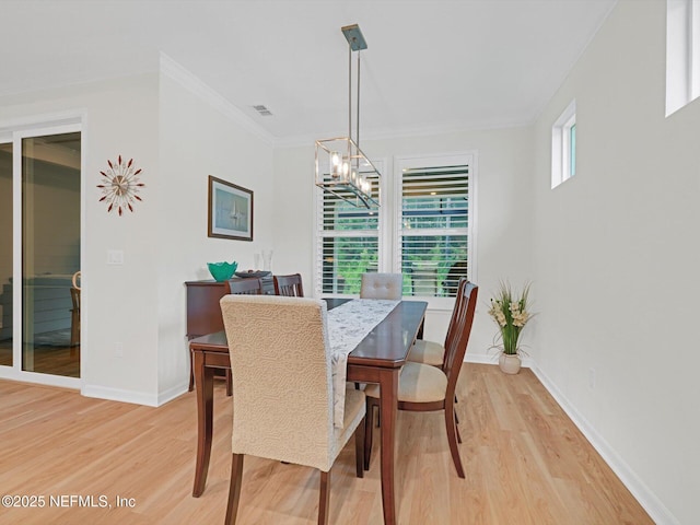 dining space featuring light wood-style flooring, baseboards, a notable chandelier, and crown molding