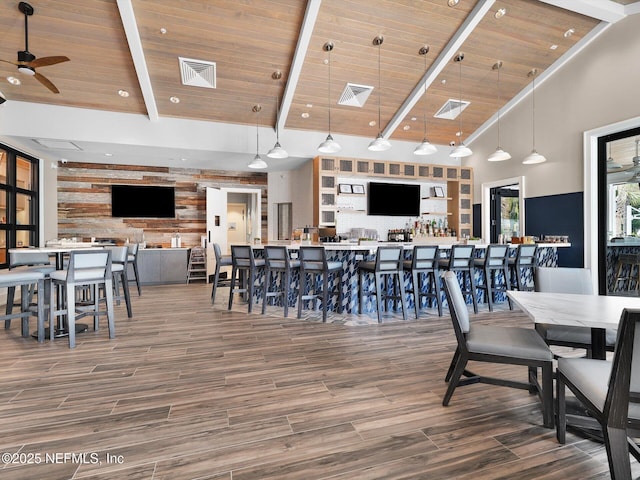 dining space featuring wood finished floors, visible vents, a ceiling fan, beamed ceiling, and wood ceiling