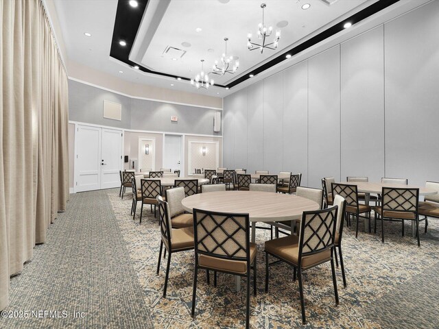 carpeted dining space featuring a high ceiling, recessed lighting, a chandelier, and a decorative wall