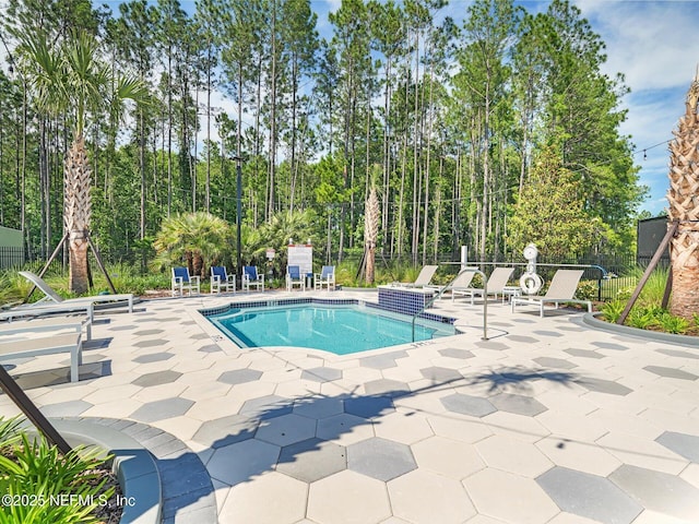 community pool with fence and a patio